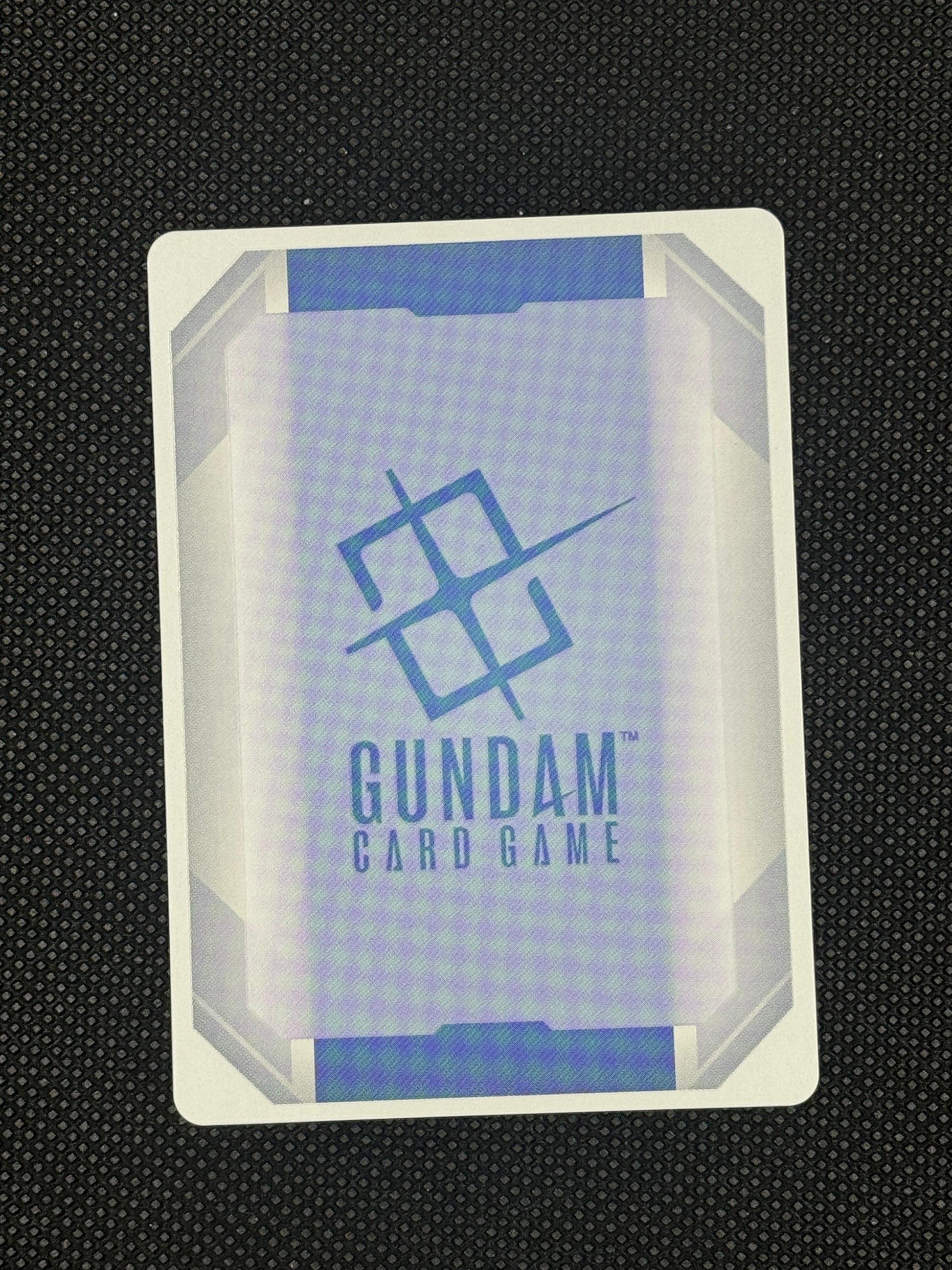 Gundam card game card with branding on a textured black background