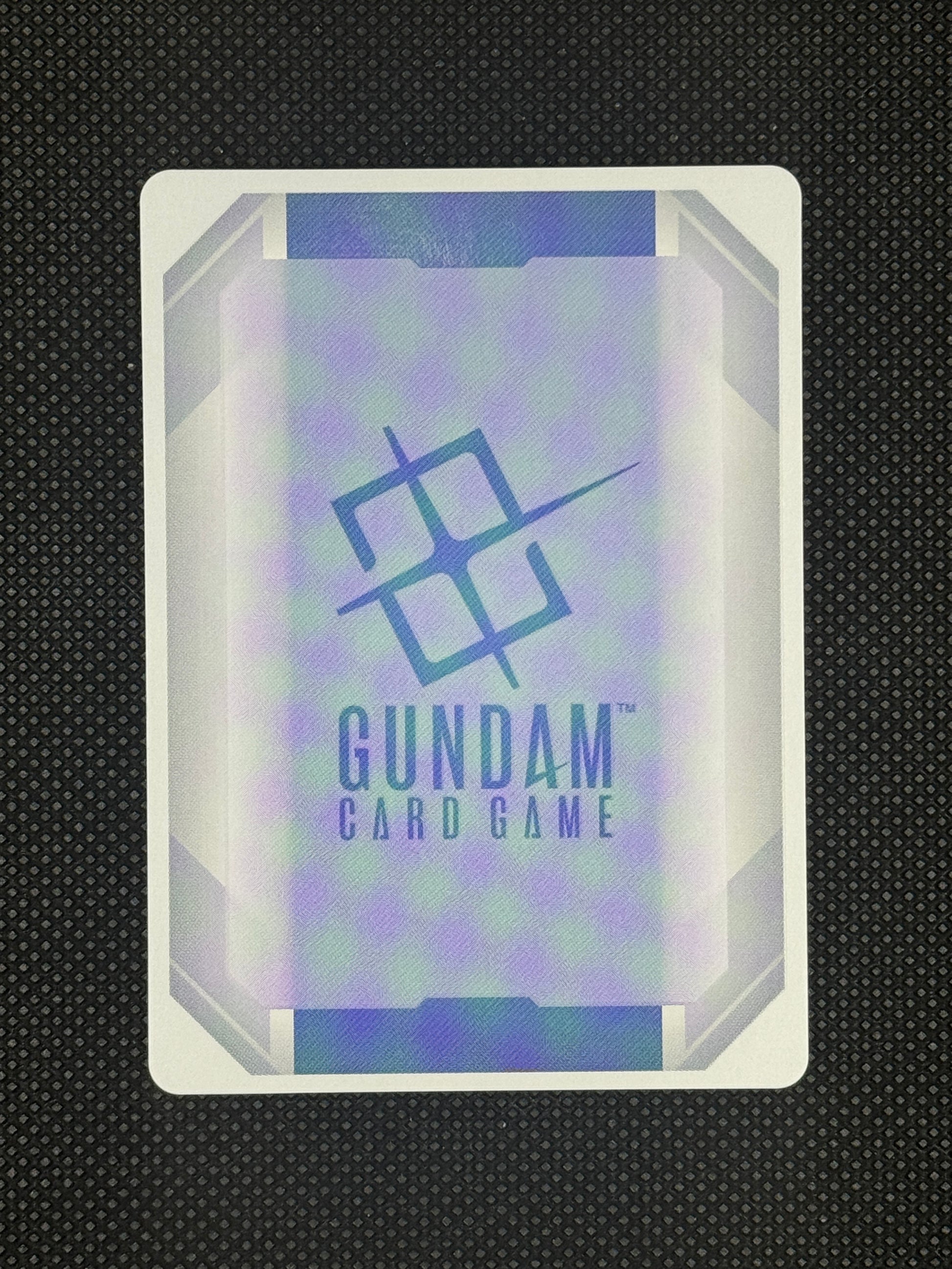 Gundam card game packaging with brand logo on a textured black background